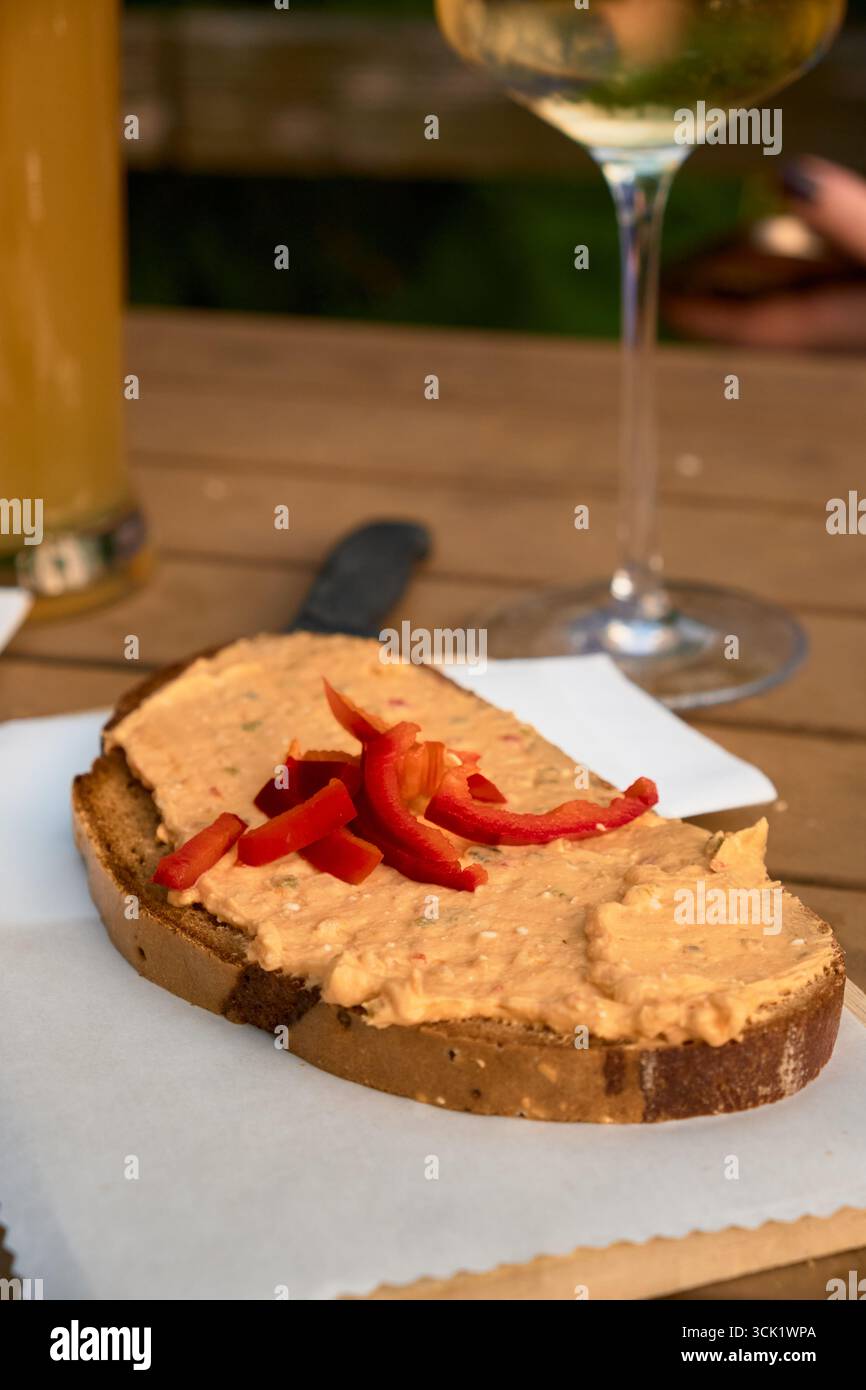 Close-up of traditional Austrian sandwich on white napkin, with partial view of wine glass and beer glass, rustic dining scene and cozy authentic food Stock Photo