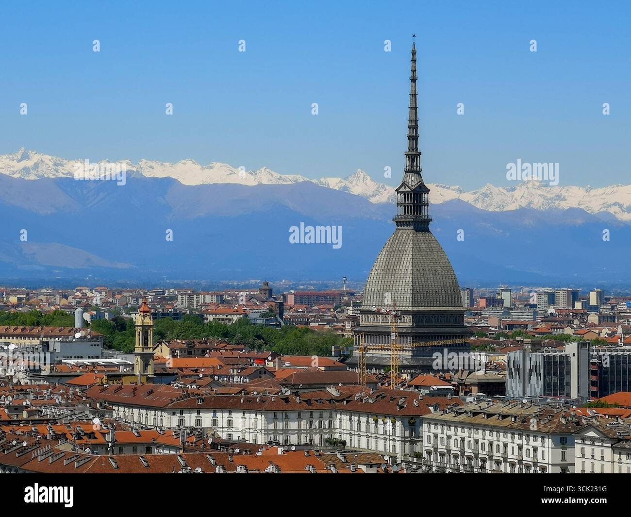 A high-angle view of the cityscape of Turin, Italy, featuring the iconic spire of the Mole Antonelliana rising above a sea of red-tiled roofs. In the - Smartphone Captured Stock Image