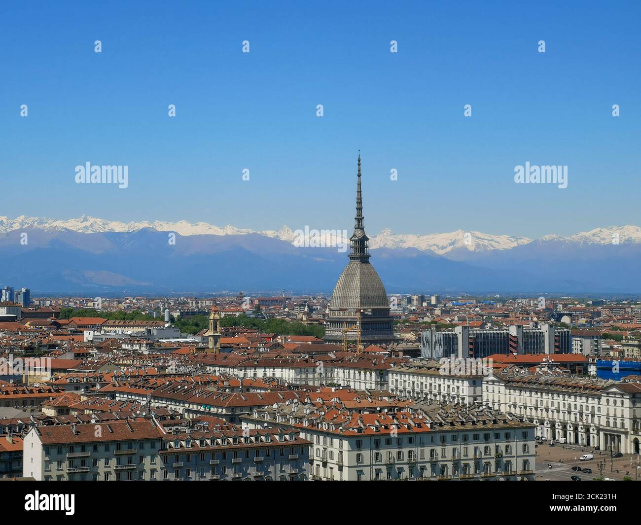 A high-angle view of the cityscape of Turin, Italy, featuring the iconic spire of the Mole Antonelliana rising above a sea of red-tiled roofs. In the - Smartphone Captured Stock Image