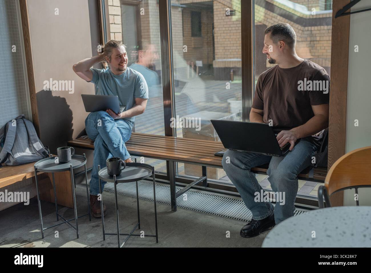 Two laughing It Software engineers working on project and programming in coffee shop. Successful start up project concept. Stock Photo