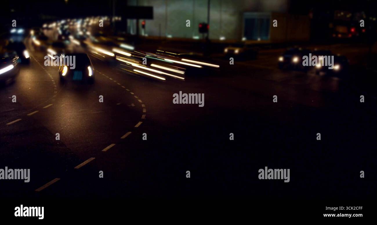 Maneuvering multiple cars through wet urban intersection at night, with glowing light trails Stock Photo