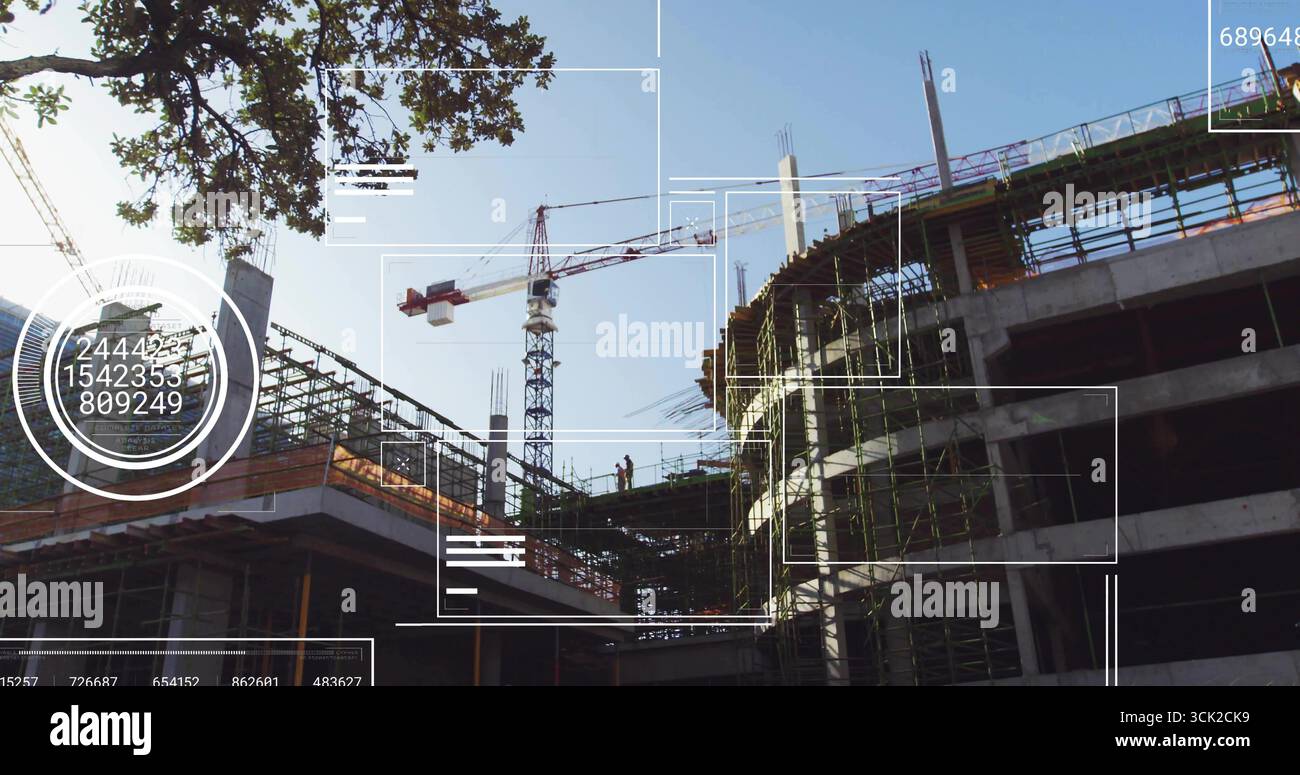 Standing construction workers wearing helmets vests on scaffolding at job site, with tower crane Stock Photo