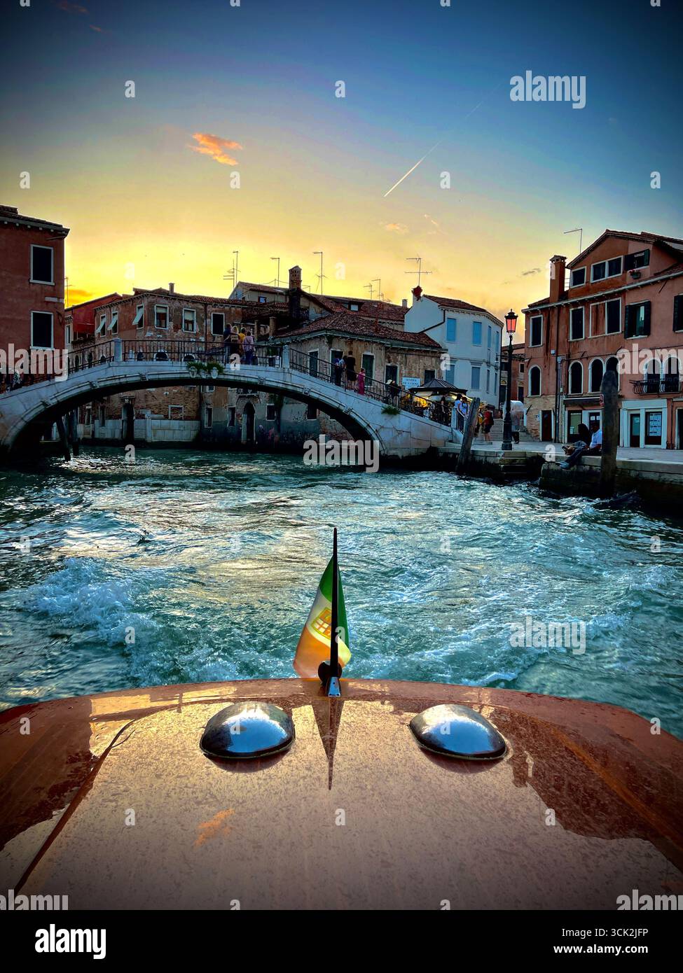 Sunset view from a water taxi in Venice, Italy, approaching Ponte San Pantalon bridge, with historic Venetian architecture illuminated by golden hour. - Smartphone Captured Stock Image