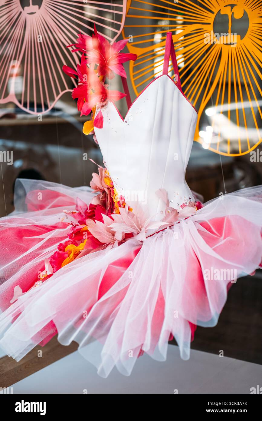 Pink and white ballerina tutu dress adorned with artificial flowers and tulle in a boutique display window. Costume craftsmanship, childhood fantasy Stock Photo