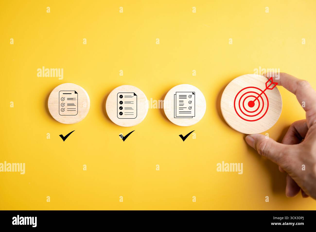 Goal planning and task completion strategy concept. Hand holding target icon after completing all checklist. Wooden blocks on yellow background progre Stock Photo