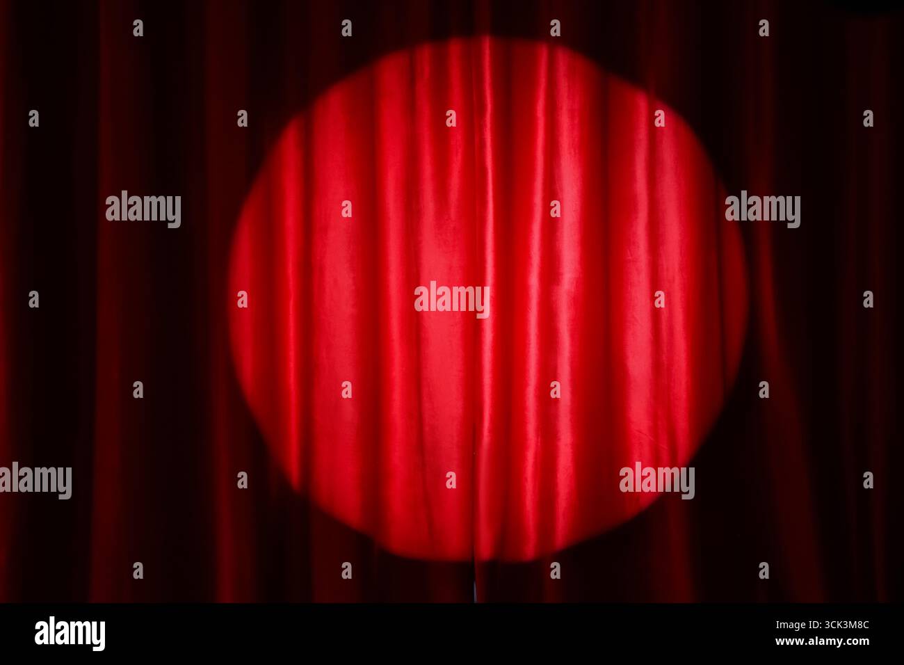 Spotlight shining on red curtain Stock Photo