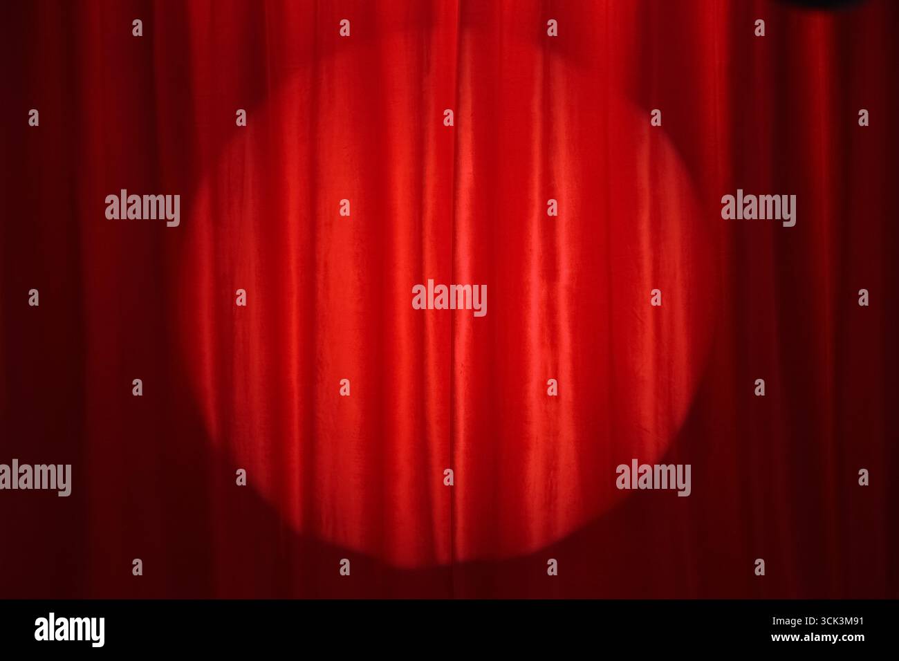Spotlight shining on red curtain Stock Photo