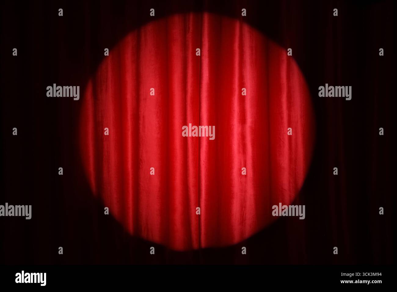 Spotlight shining on red curtain Stock Photo