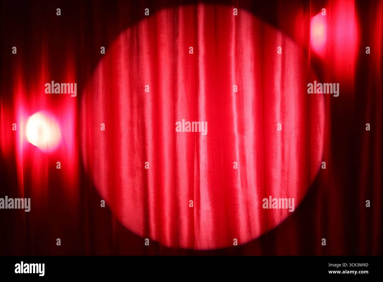 Shining spotlight on red curtain Stock Photo