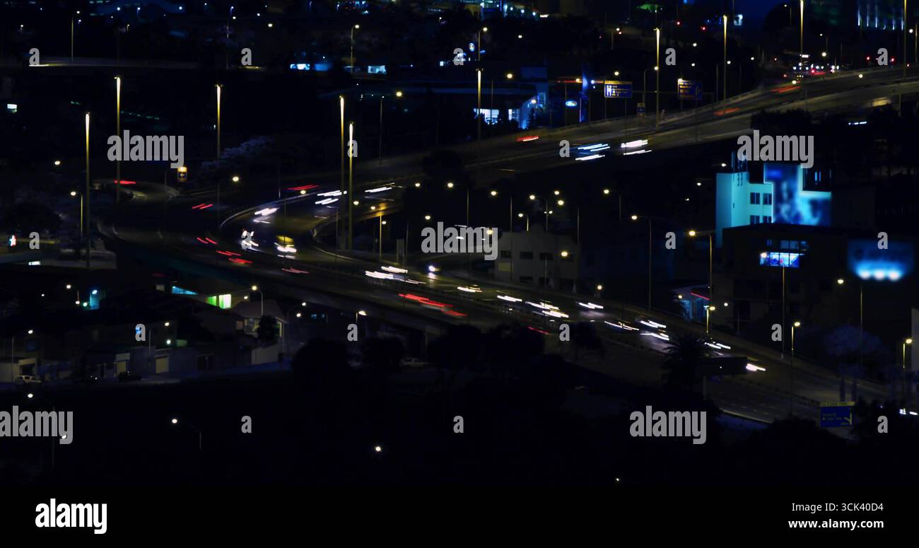 Showcasing curved highway interchange streaming light trails at night amid glowing streetlights Stock Photo