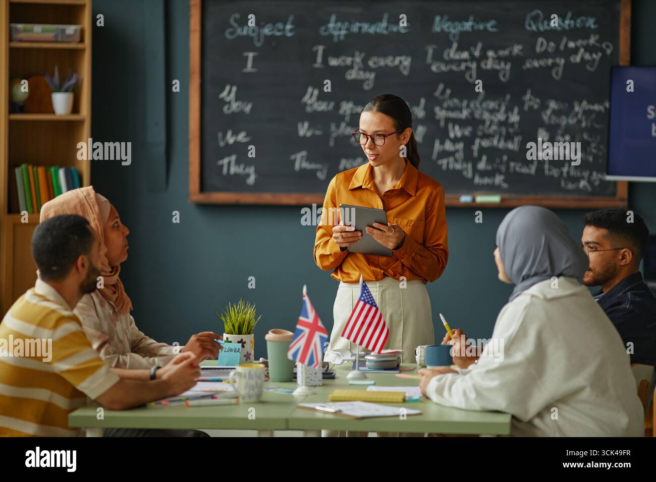 Young Caucasian Woman Teaching Multiethnic Adults Using Digital Tablet Stock Photo