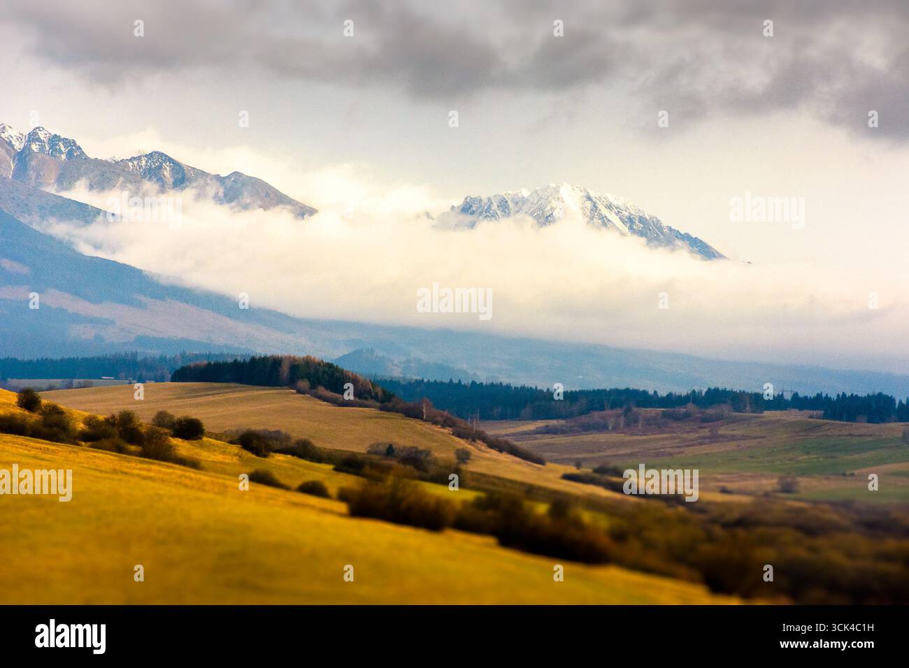 rural fields near Tatra Mountains in autumn season. beautiful view of countryside area of slovakia with forest on the hills. gorgeous mountain ridge w Stock Photo