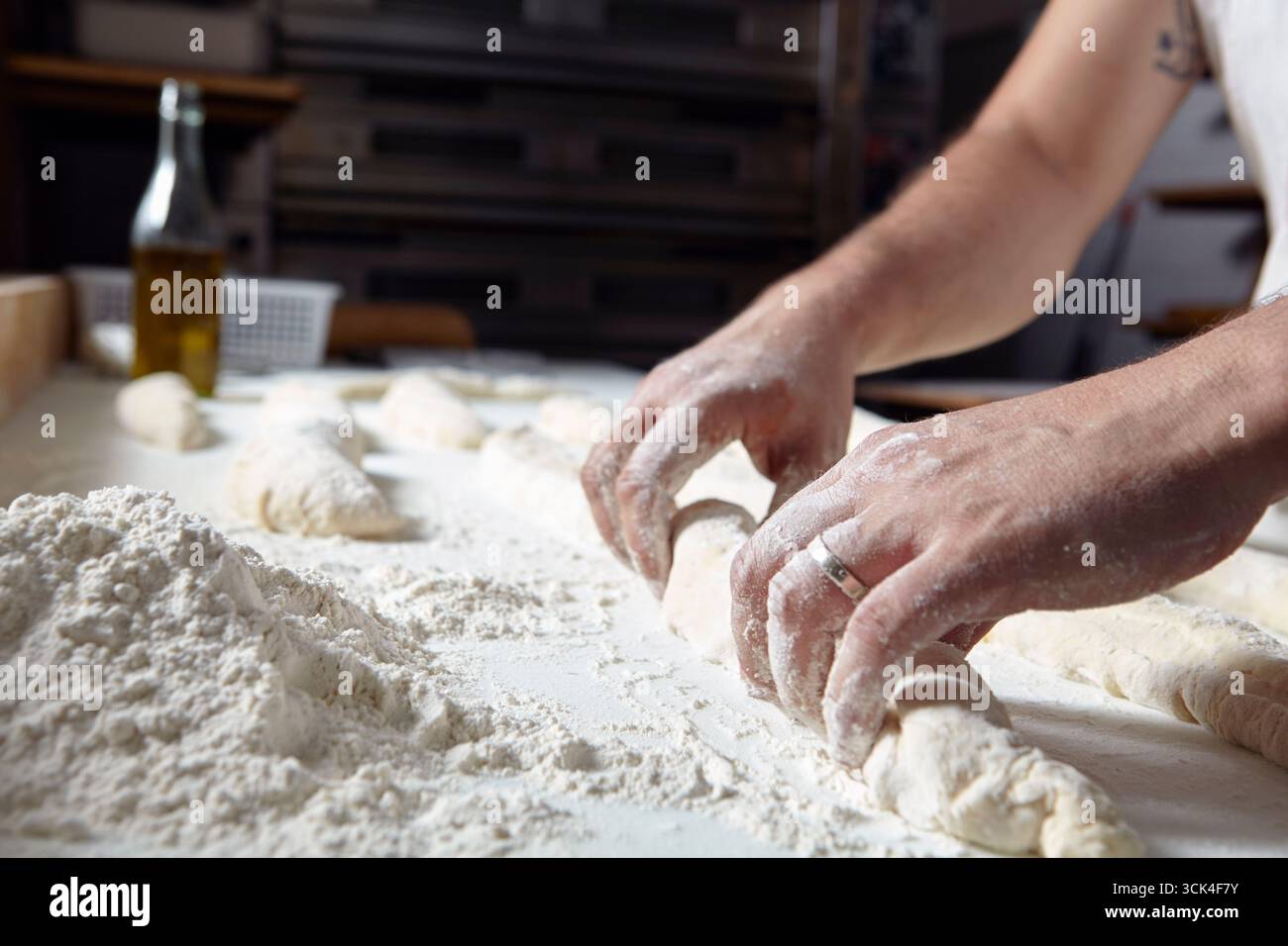 Baker kneads dough on a floured work surface Stock Photo
