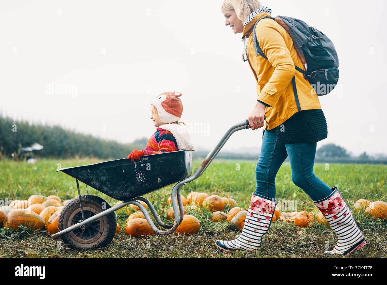 Woman carrying child in wheelbarrow for Halloween party Stock Photo - Alamy