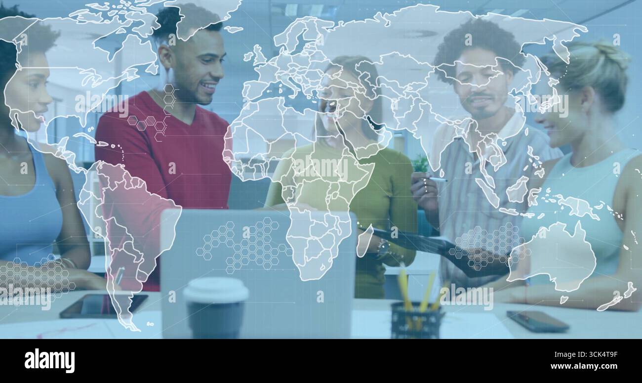 Collaborating professionals standing around table in office, with laptop tablet world map overlay Stock Photo