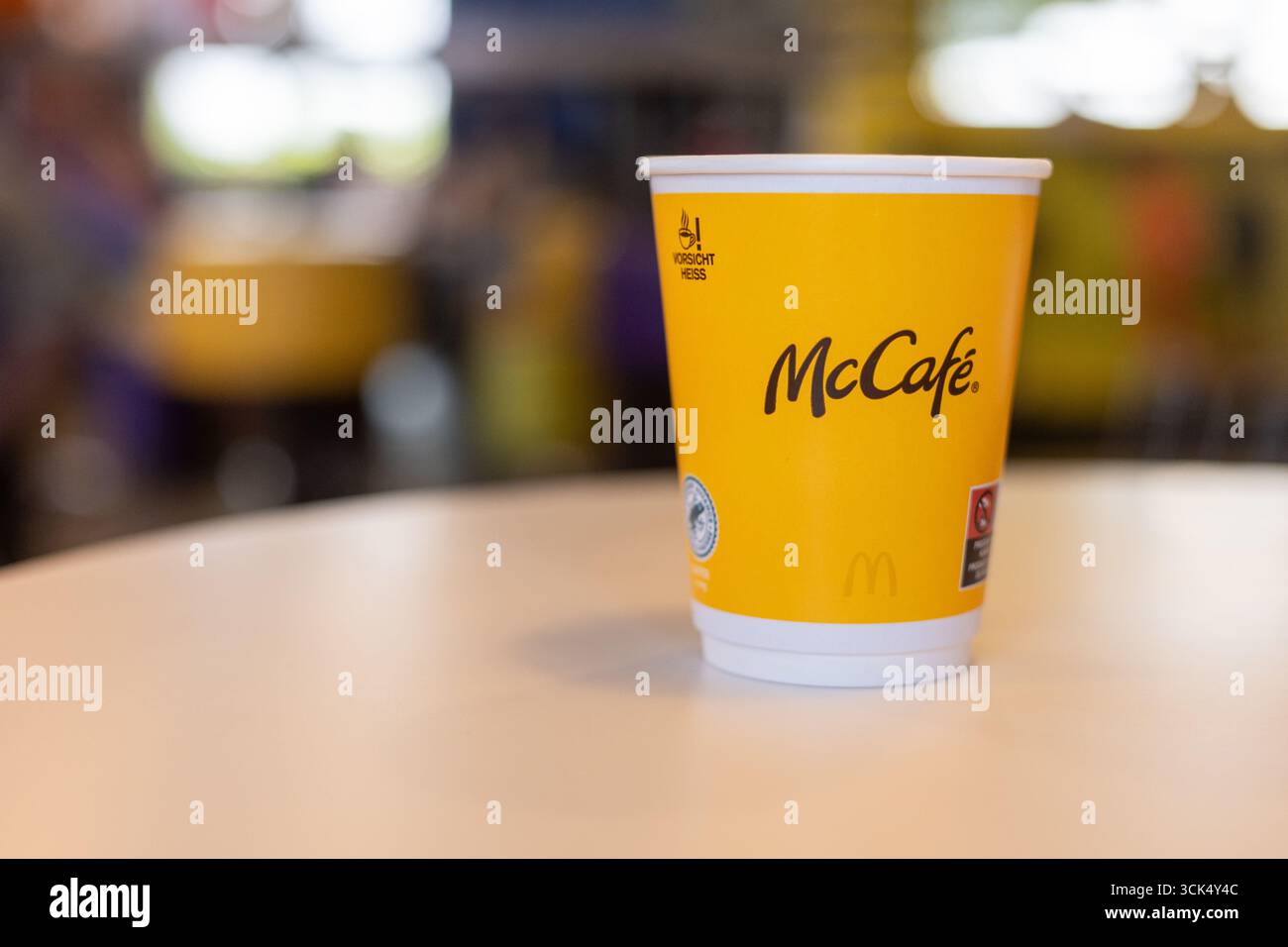 Kerpen, Germany - August, 9, 2025: Yellow McCafe cup on a table in McDonalds interior Stock Photo