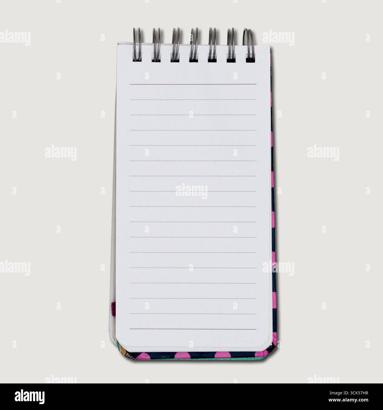 A small notepad with a spiral binding and blank lined pages for writing notes or lists. Stock Photo