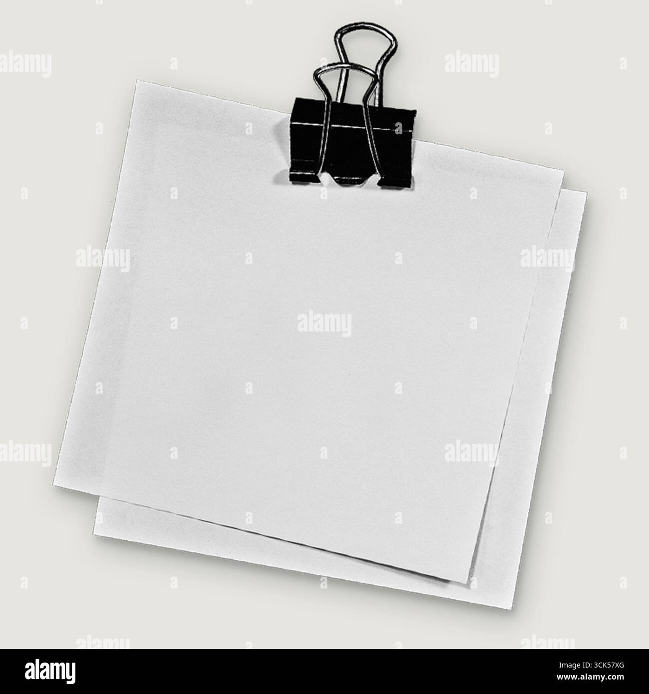 A blank notepad held by a black paper clip, ready for notes or reminders. Stock Photo