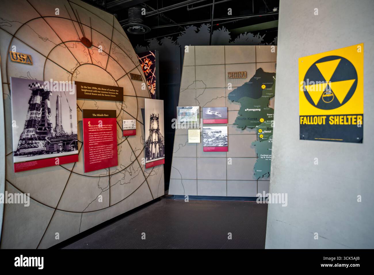 Smithsonian National Museum Of American History Cold War Exhibit Washington DC // WASHINGTON DC — The Smithsonian National Museum of American History features an exhibit on the Cold War, highlighting global tensions and the threat of nuclear war between the United States and the Soviet Union in the late 1950s. Displays include information on the 'Missile Race,' images of rocket launch sites, and a map of North Korea. A prominent sign indicates a fallout shelter, underscoring the pervasive fear of nuclear conflict during that era. Stock Photo