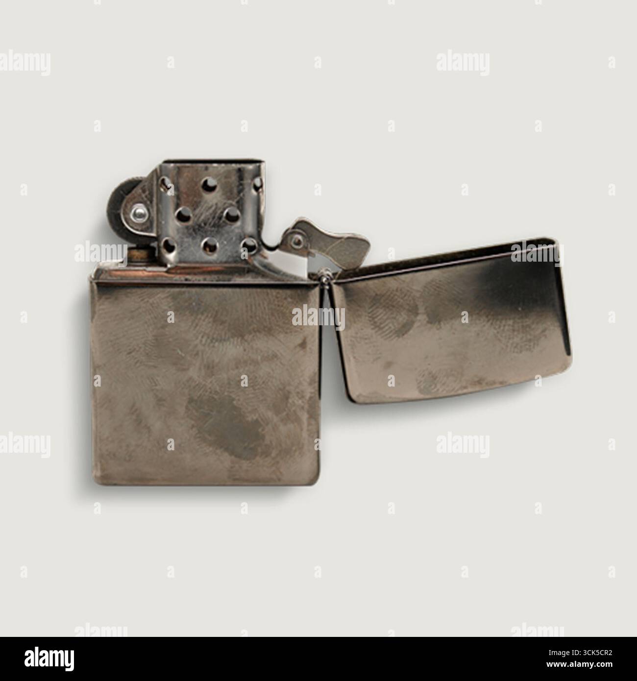 A metallic lighter with an open lid, designed for igniting flames. Stock Photo