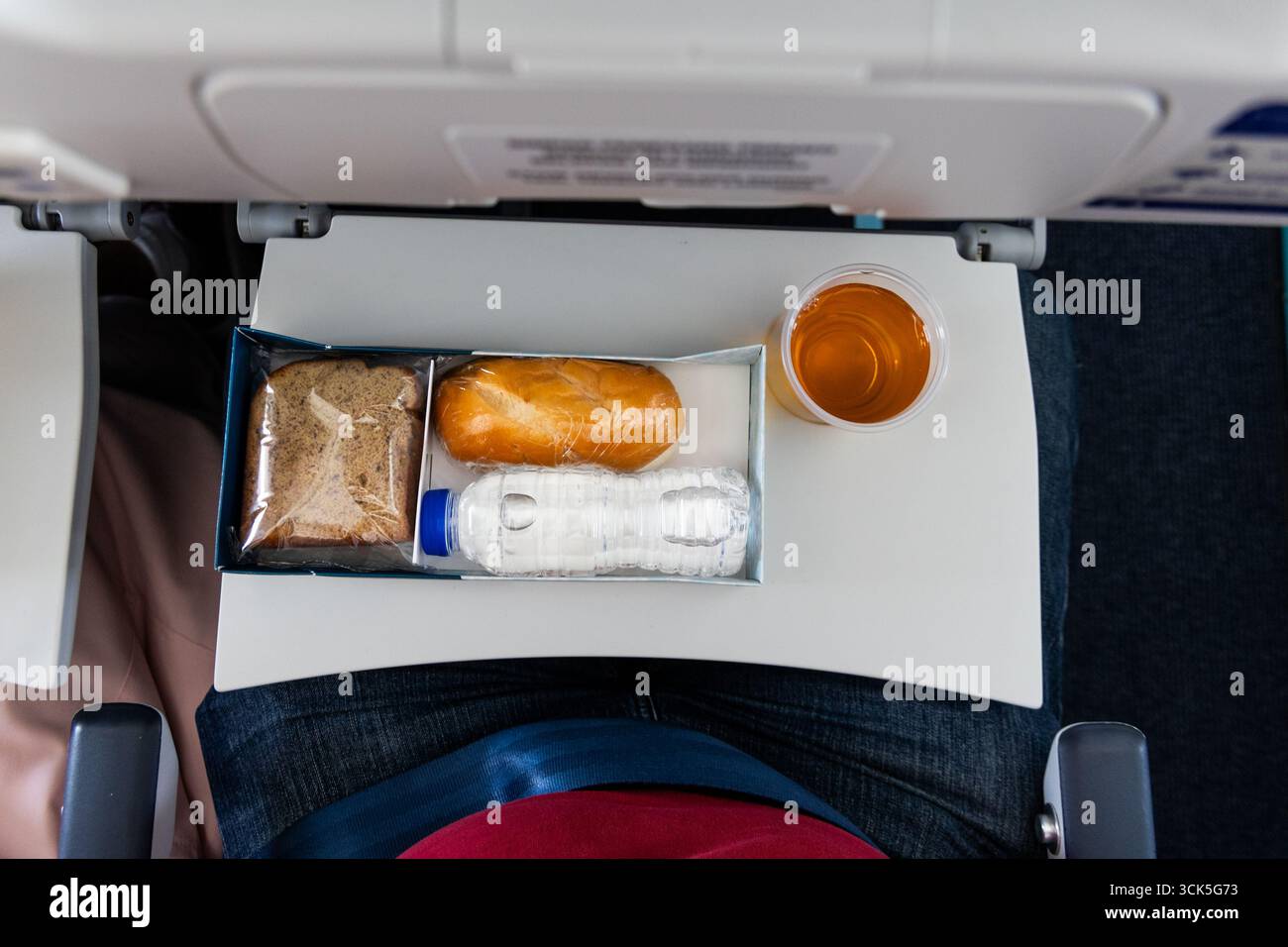 Overhead view of simple mealbox with light snack, apple juice and water served in short haul flight Stock Photo