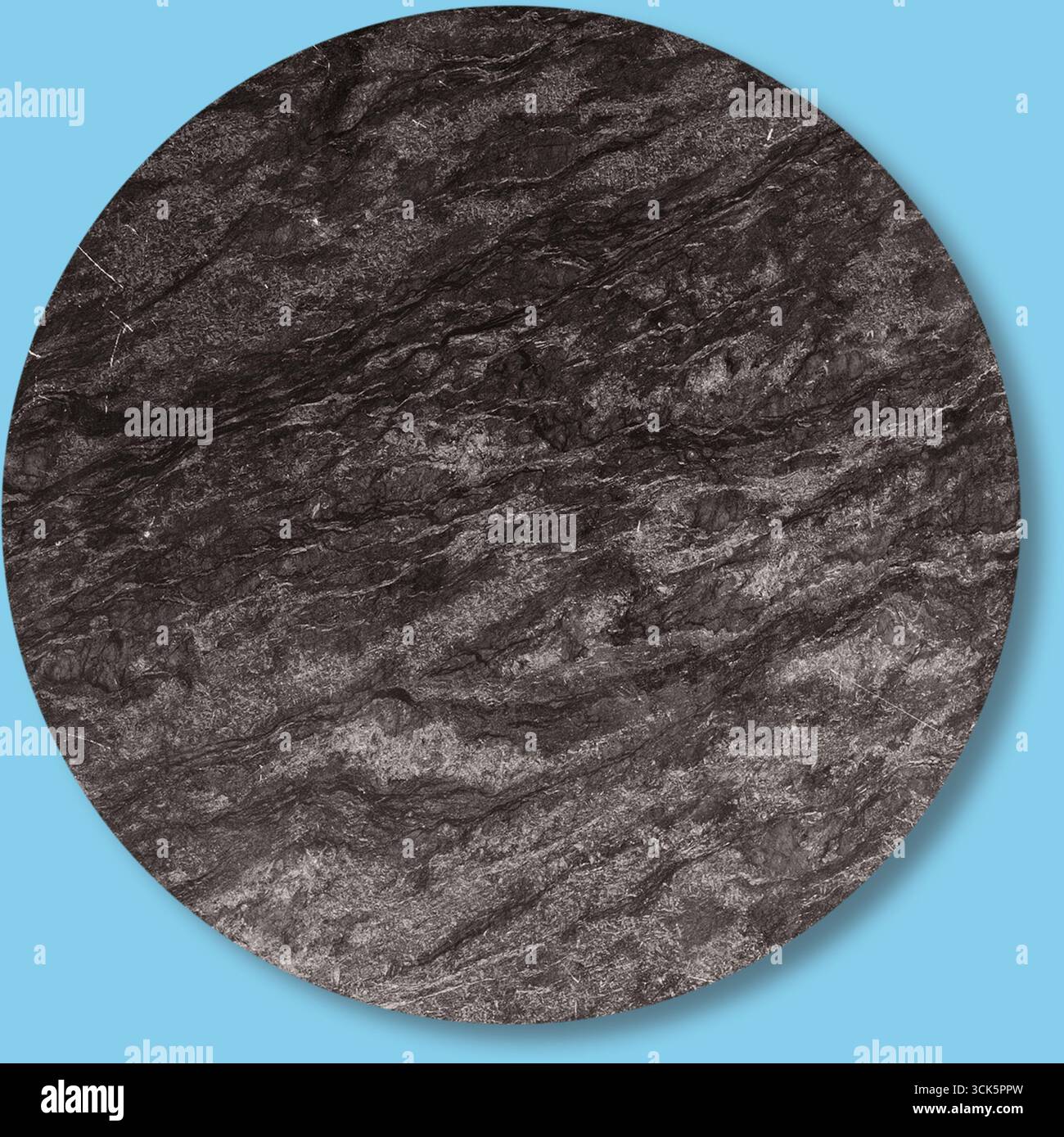 A textured circular surface resembling dark stone or mineral with subtle patterns. Stock Photo