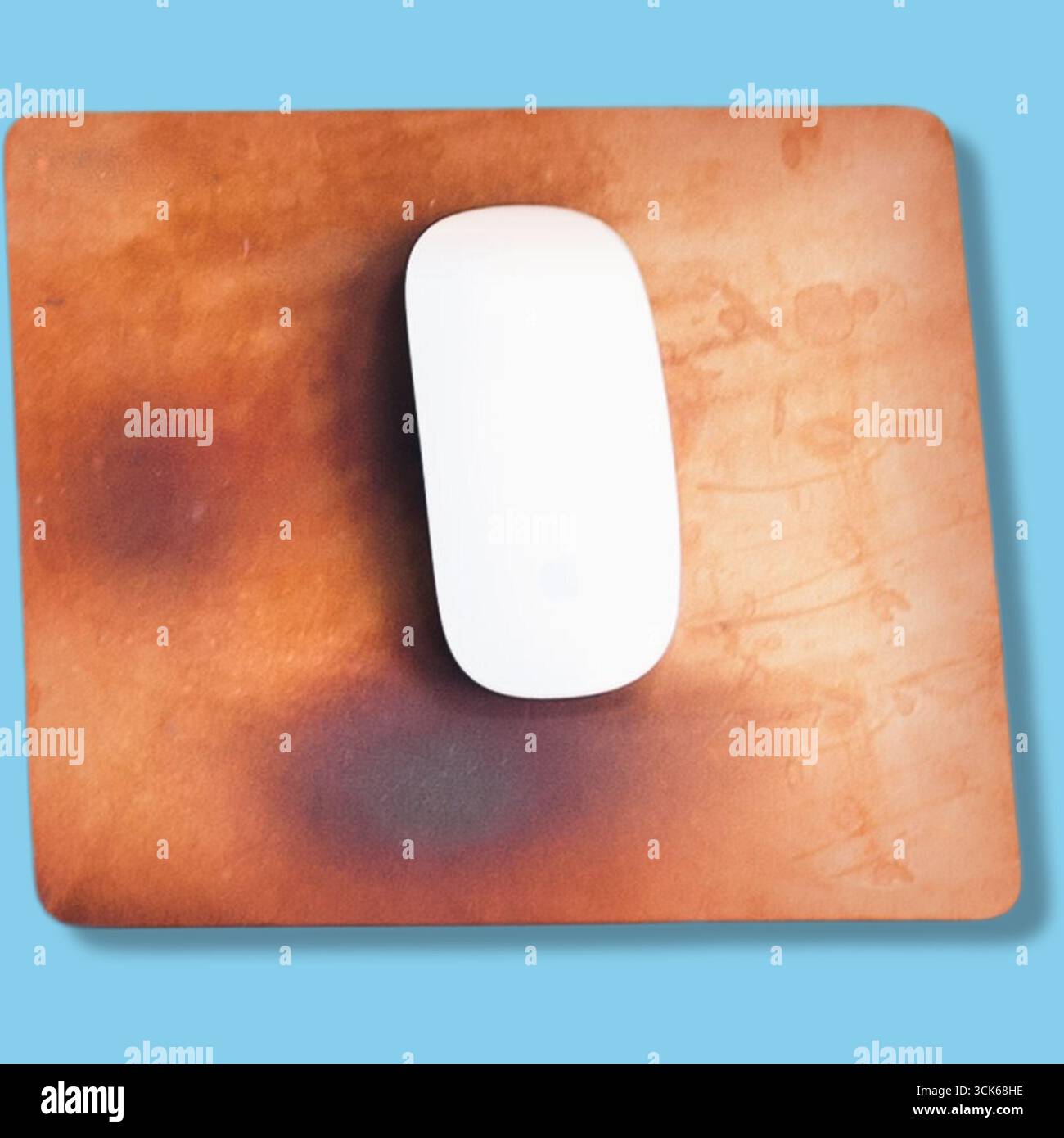 A white computer mouse sits on a textured brown mouse pad, showcasing a simple workspace setup. Stock Photo