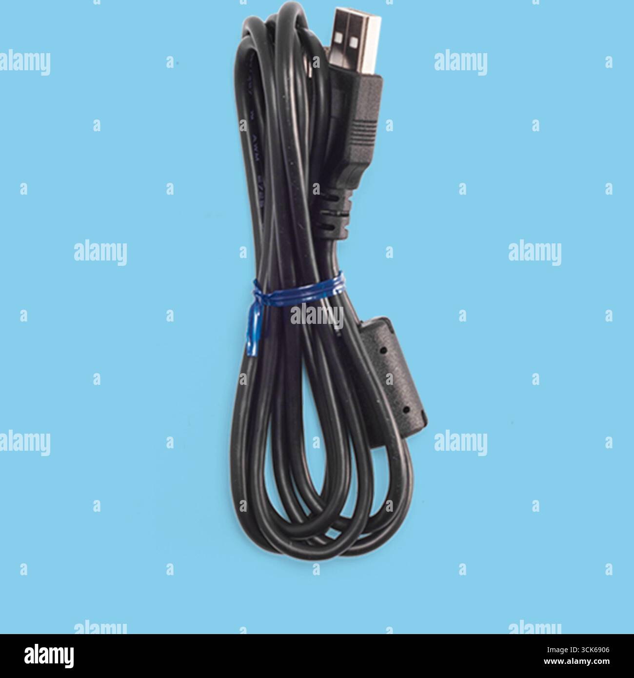 A coiled black USB cable used for data transfer and charging devices. Stock Photo