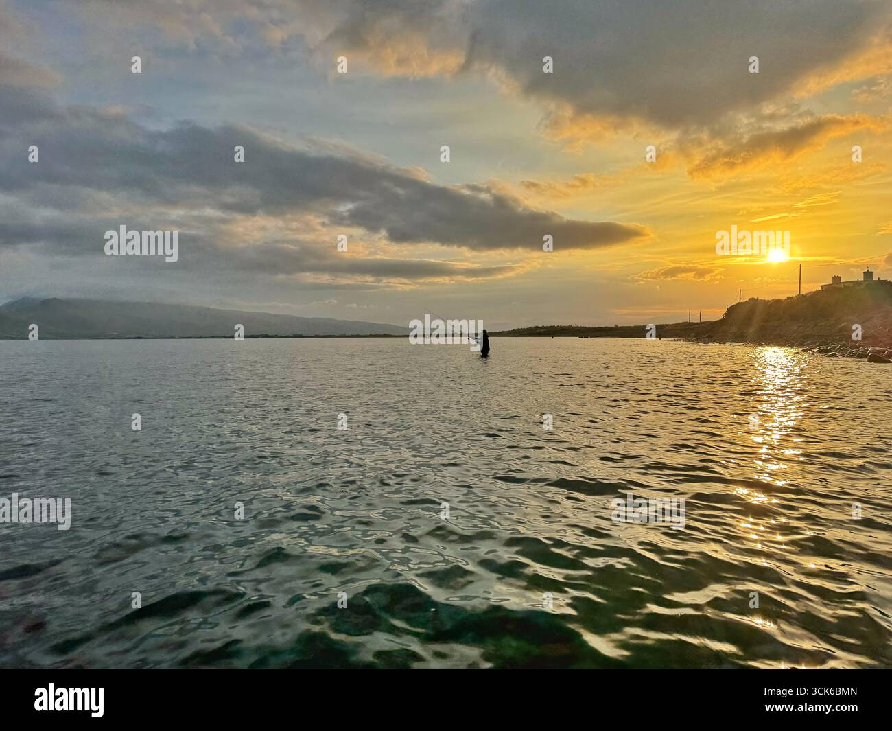 An angler fishing in an estuary in county Kerry, south west Ireland, shortly after sunrise. - Smartphone Captured Stock Image