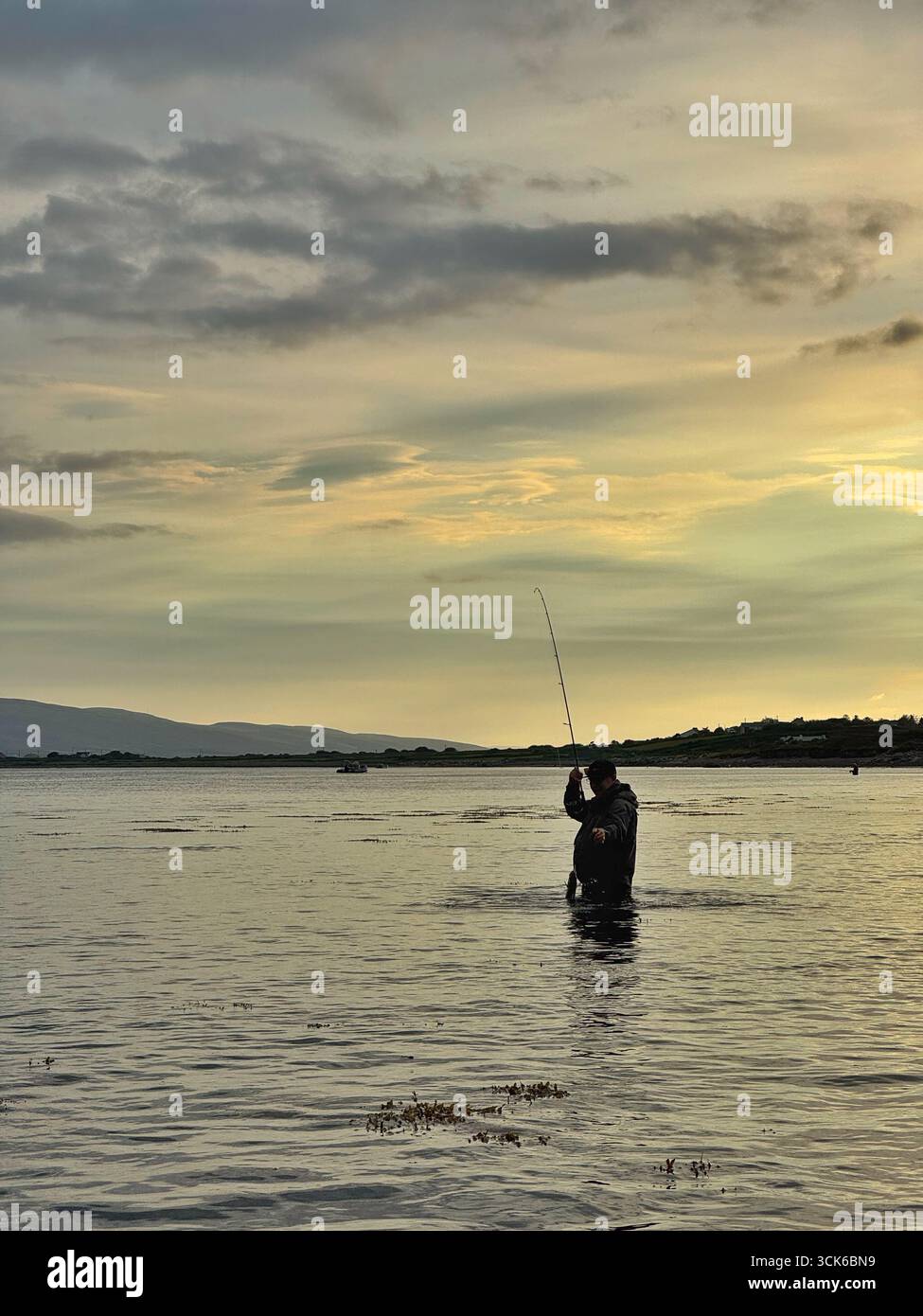 An angler fishing in an estuary in county Kerry, south west Ireland, shortly after sunrise. - Smartphone Captured Stock Image