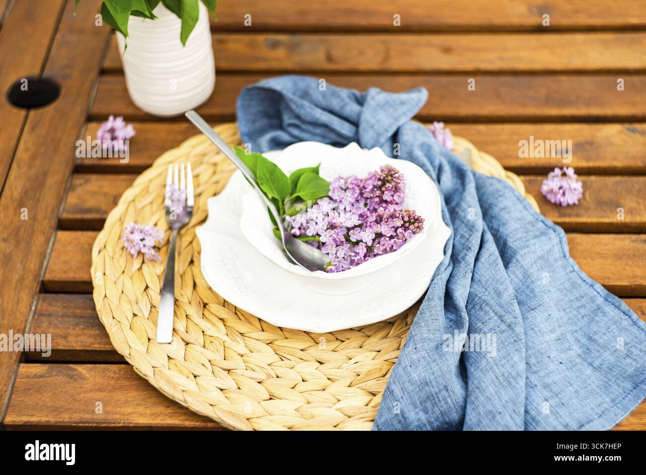 Spring place setting with lilac flowers on outdoor table Stock Photo