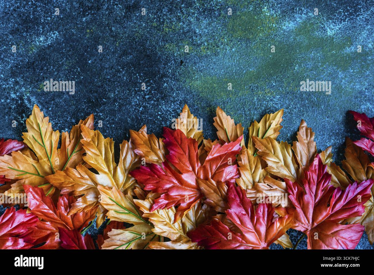 Bright red and yellow fake maple leaves on the concrete background Stock Photo