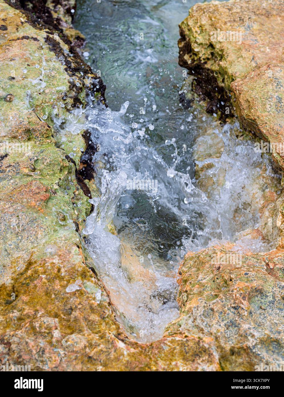 Translucent Water With Rocks Crystal-clear water flows between textured rocks, splashing through a ...