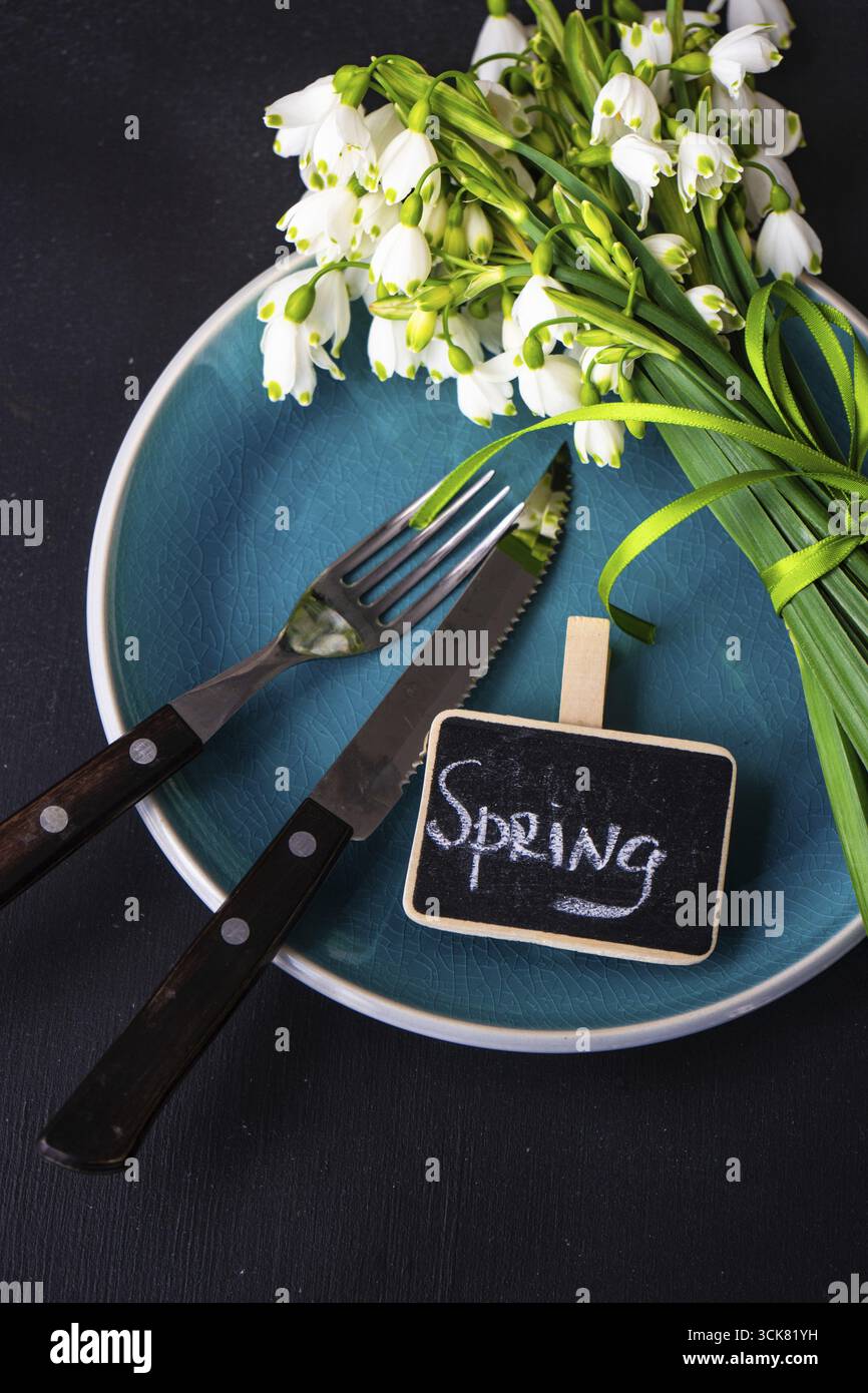 Feastive table setting for holiday Easter dinner decorated with spring snowdrop flowers on rustic table with copy space Stock Photo