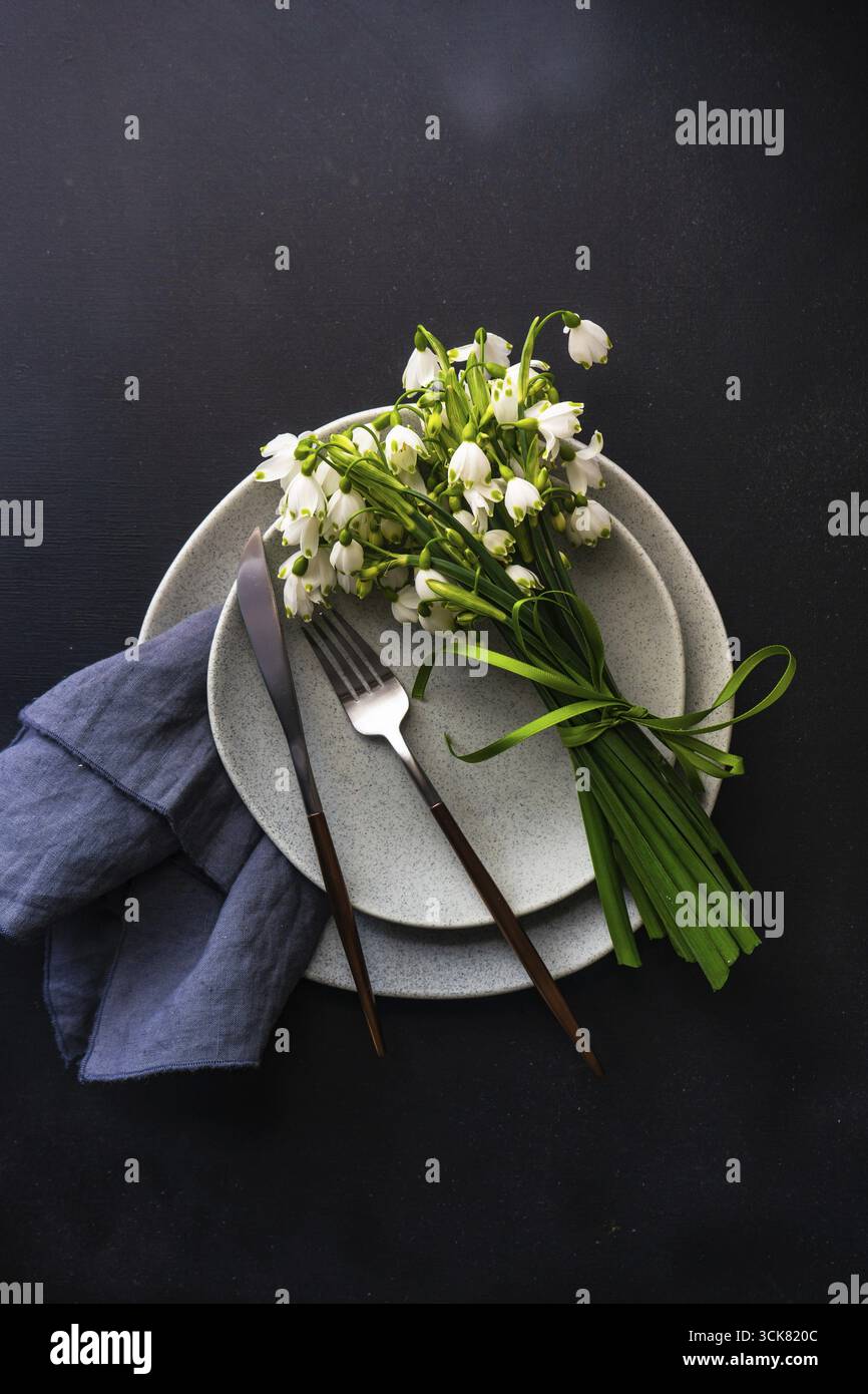 Feastive table setting for holiday Easter dinner decorated with spring snowdrop flowers on rustic table with copy space Stock Photo