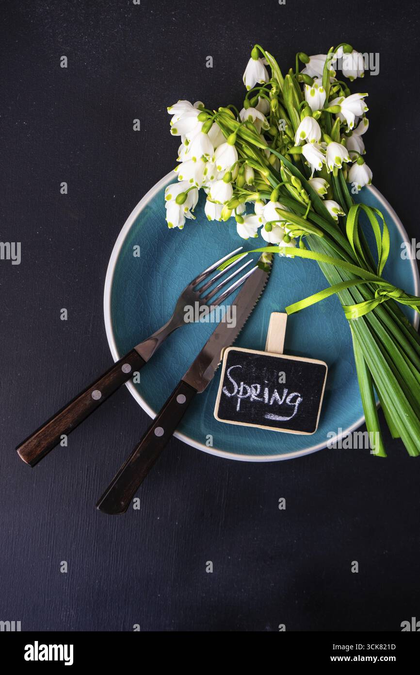 Feastive table setting for holiday Easter dinner decorated with spring snowdrop flowers on rustic table with copy space Stock Photo