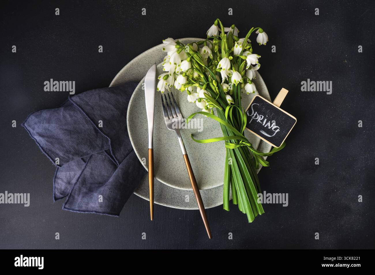 Feastive table setting for holiday Easter dinner decorated with spring snowdrop flowers on rustic table with copy space Stock Photo