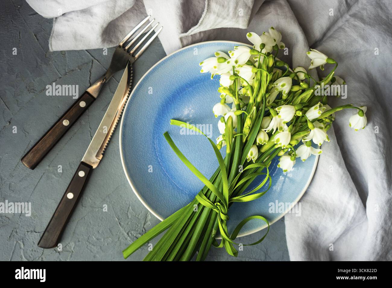 Feastive table setting for holiday Easter dinner decorated with spring snowdrop flowers on rustic table with copy space Stock Photo