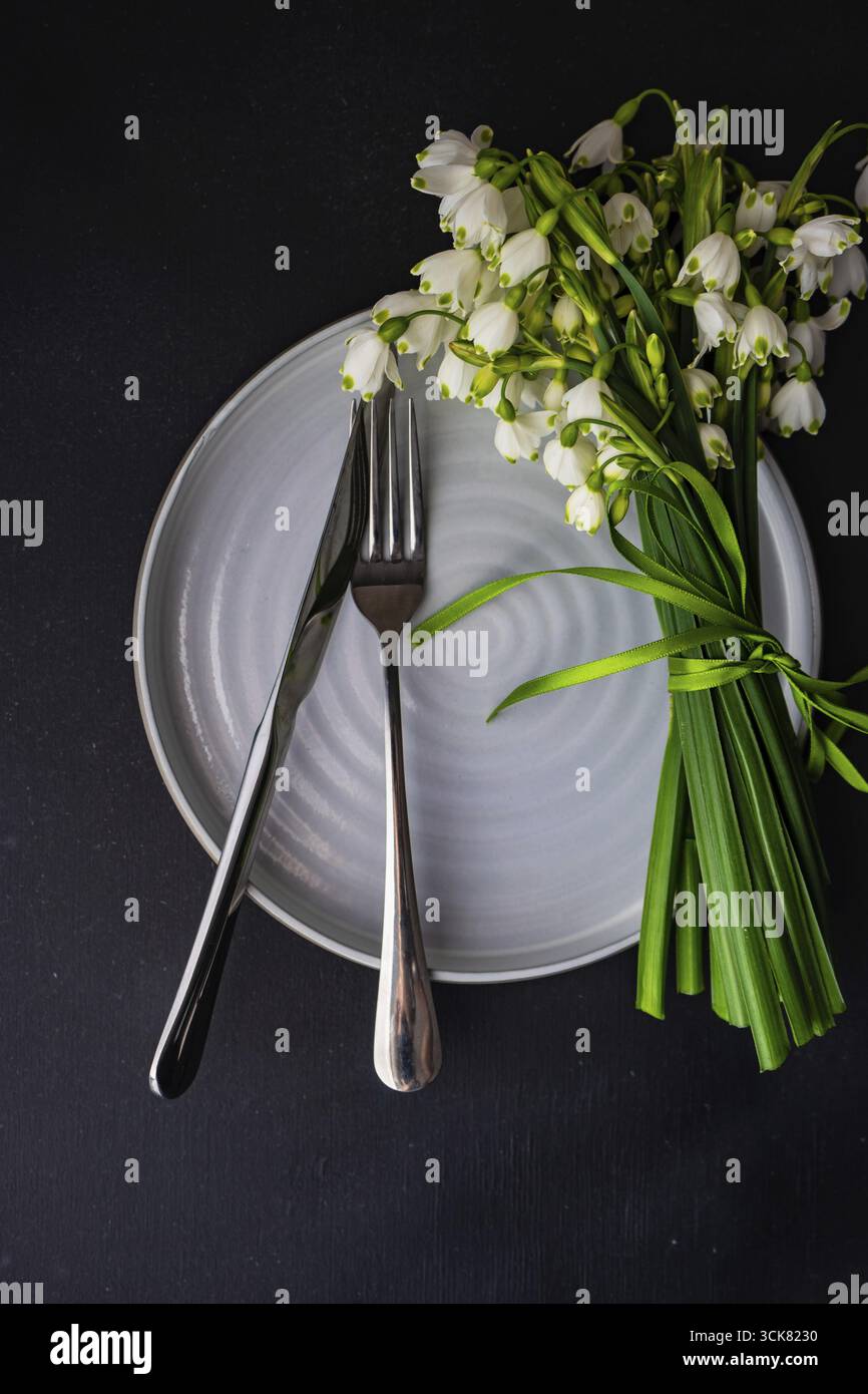 Feastive table setting for holiday Easter dinner decorated with spring snowdrop flowers on rustic table with copy space Stock Photo