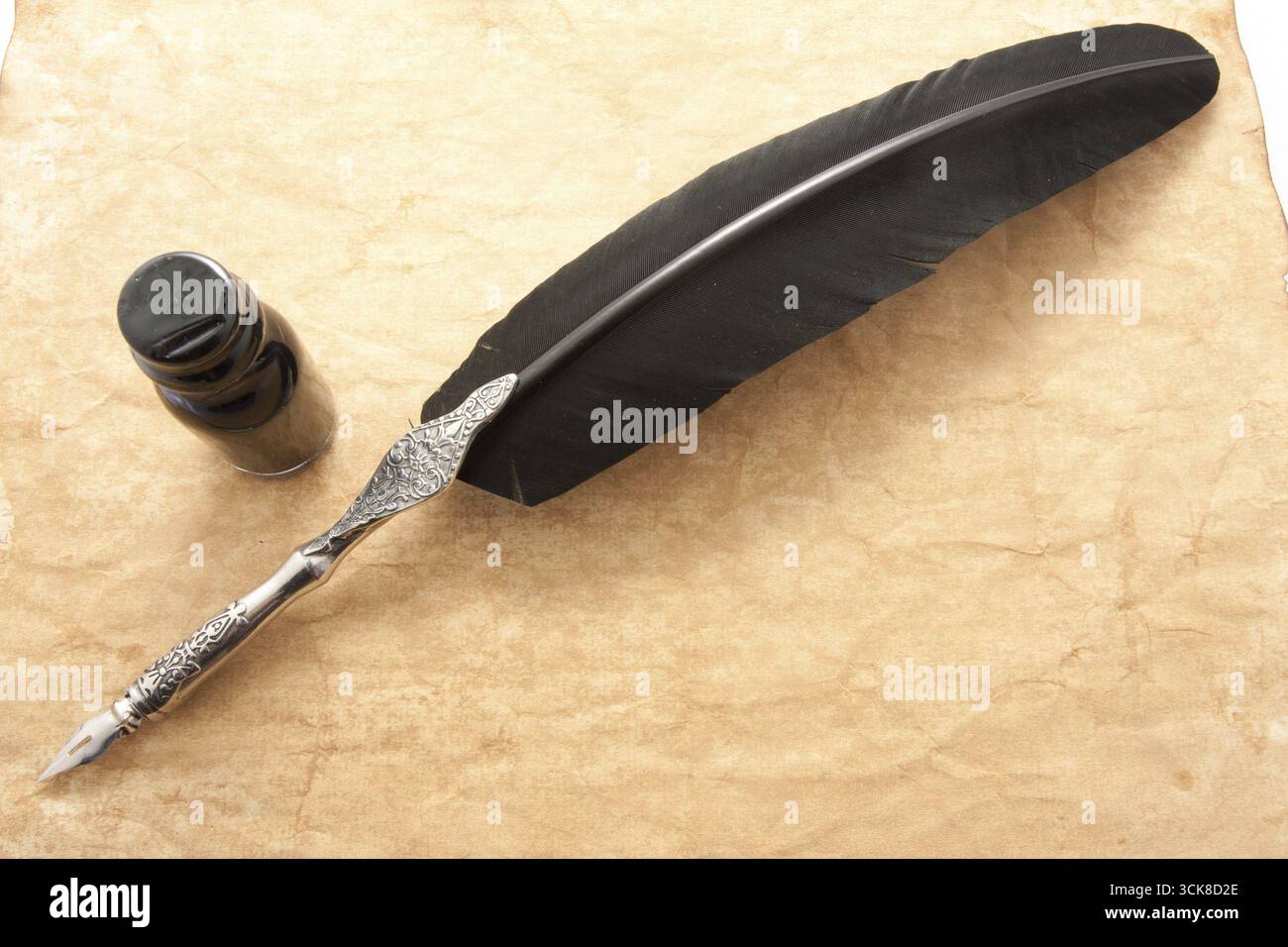 Feather pen and ink bottle on old paper background Stock Photo - Alamy