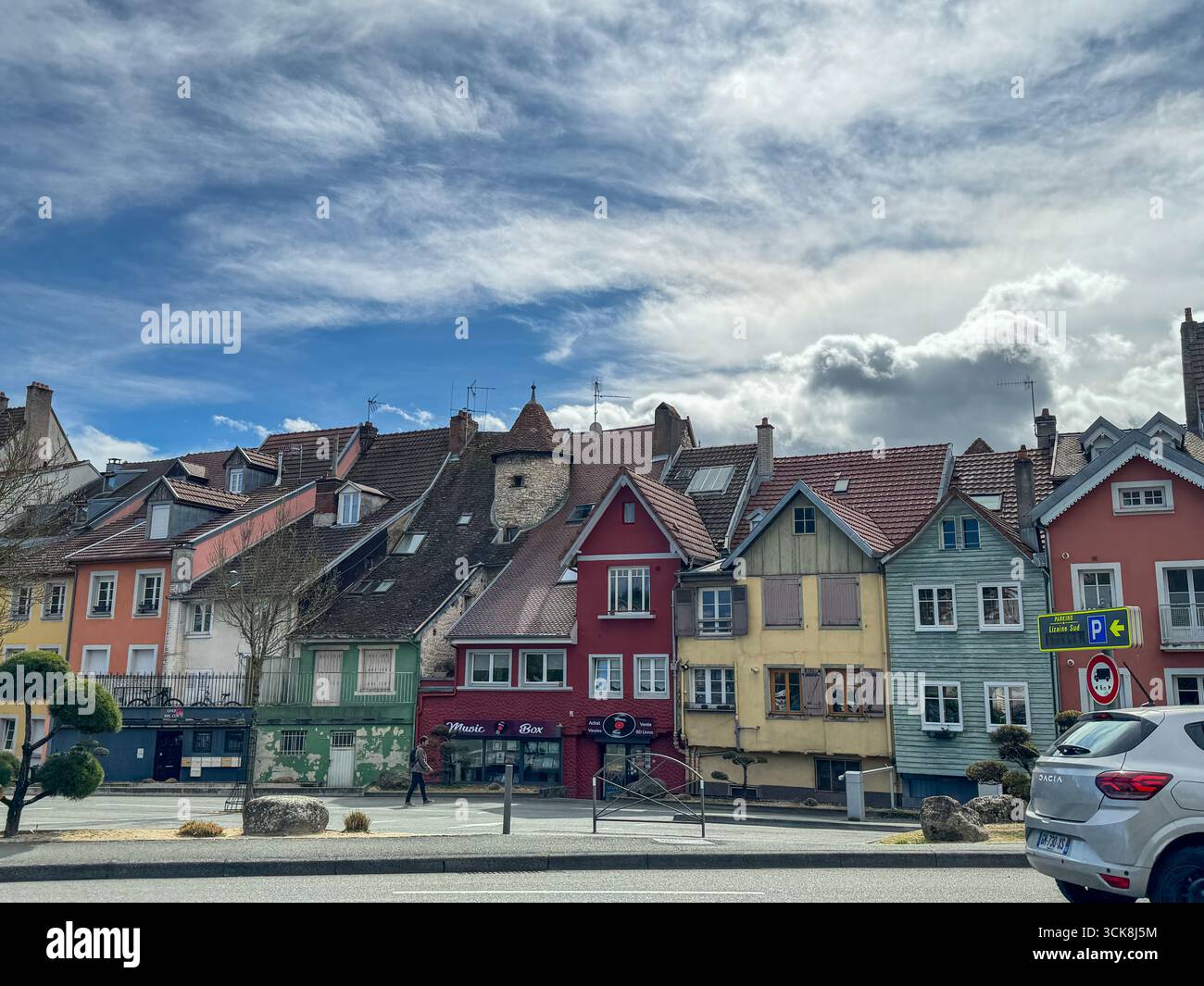 Colorful traditional houses in Monbeliard, France with tiled roofs, dormer windows, vibrant facade, cloudy sky, and lively urban street scene - Smartphone Captured Stock Image