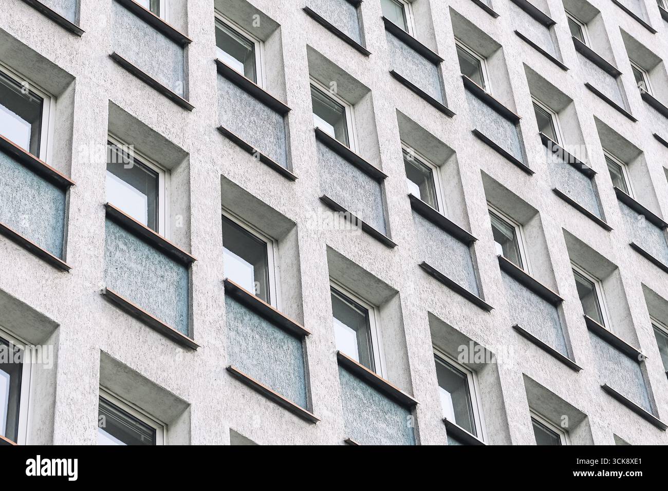 Facade of apartment building with repetitive windows. Urban residential block exterior. Modern architecture with geometric pattern design. Stock Photo