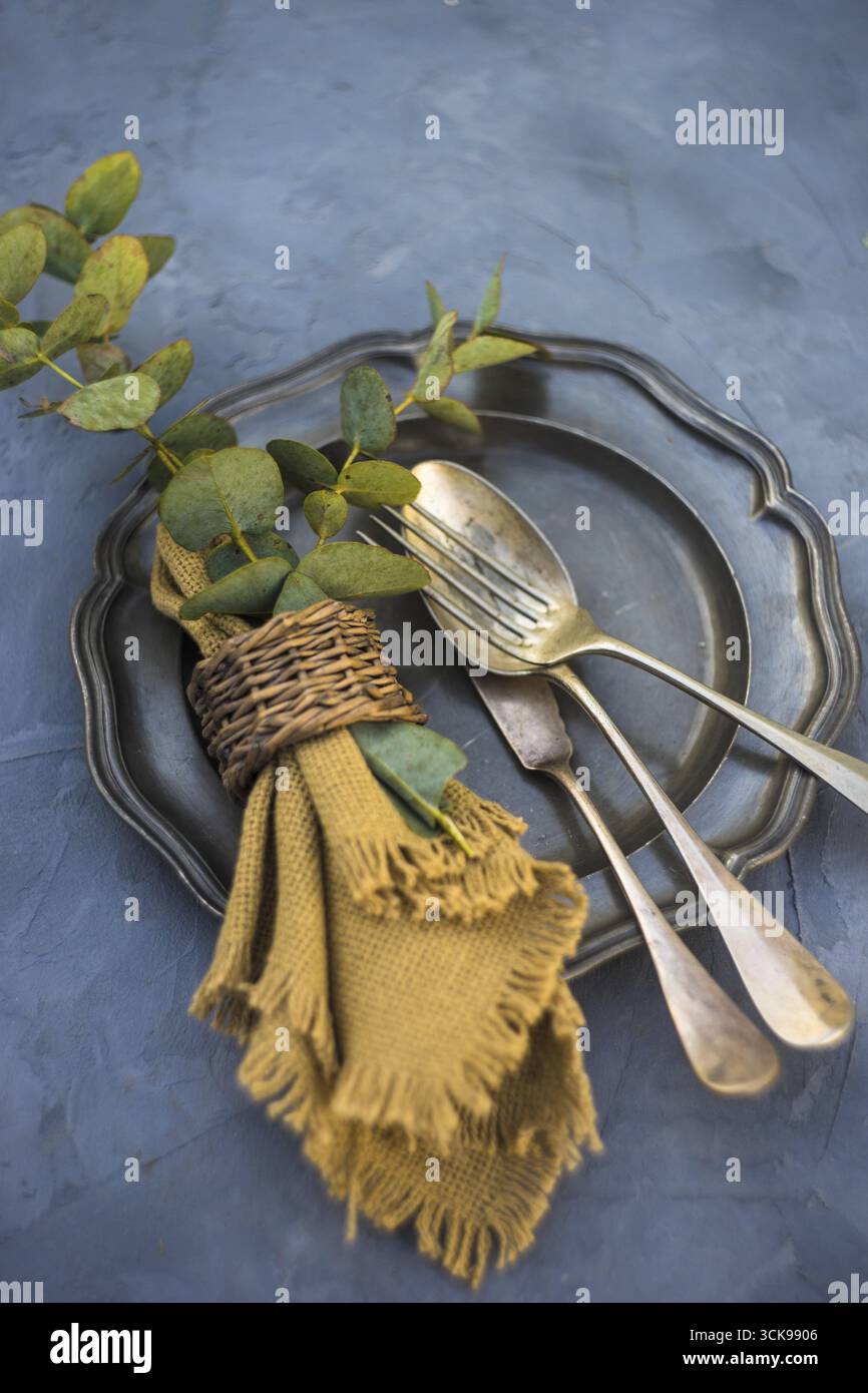 Rustic table setting with vintage silverware and plates on concrete table Stock Photo