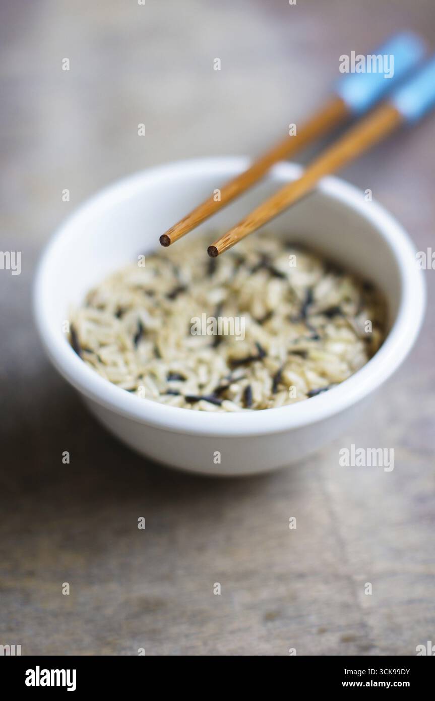Bowl of rice with wooden chopsticks and a wood place mat Stock Photo