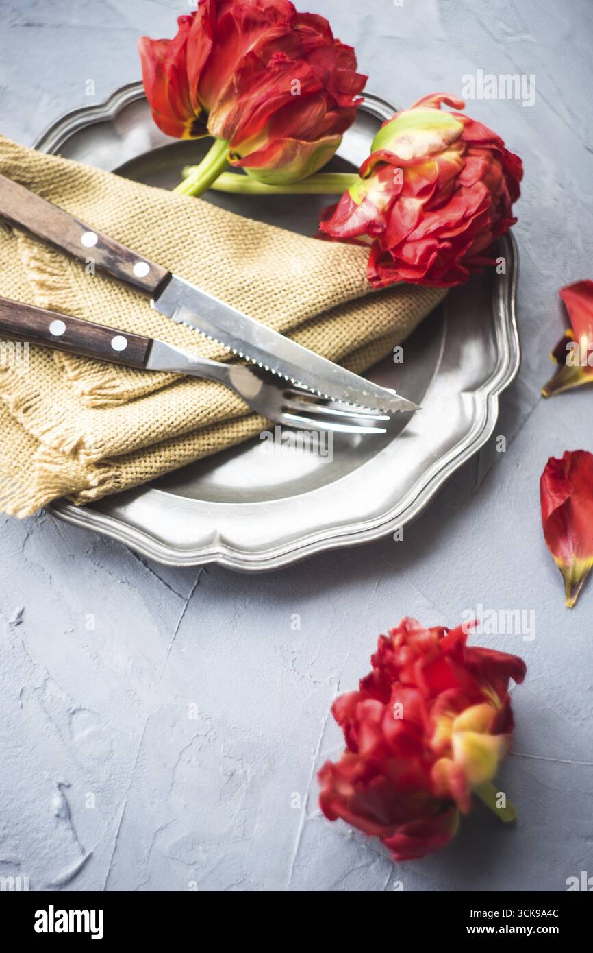 Summer table setting decorated with Red Princess tulips on rustic background Stock Photo