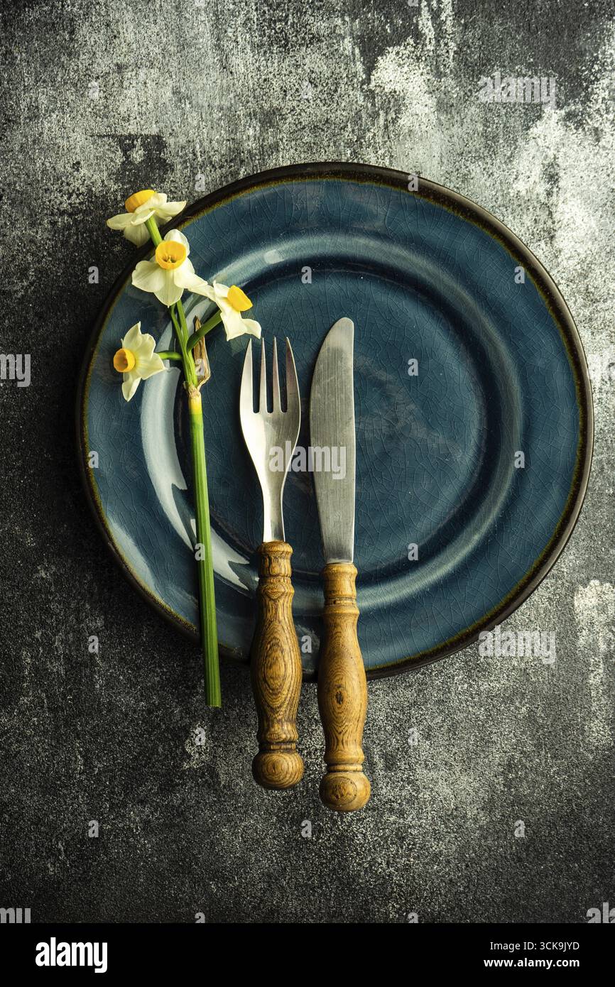Minimalistic spring table setting decorated with fresh daffodil flowers on concrete background Stock Photo