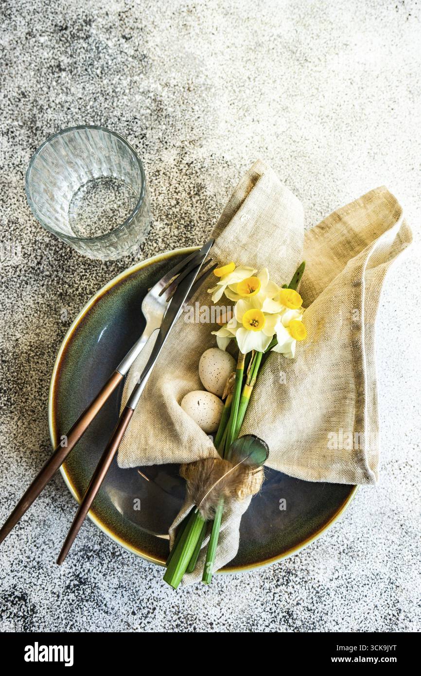 Minimalistic table setting for easter festive dinner decorated with daffodil flowers Stock Photo