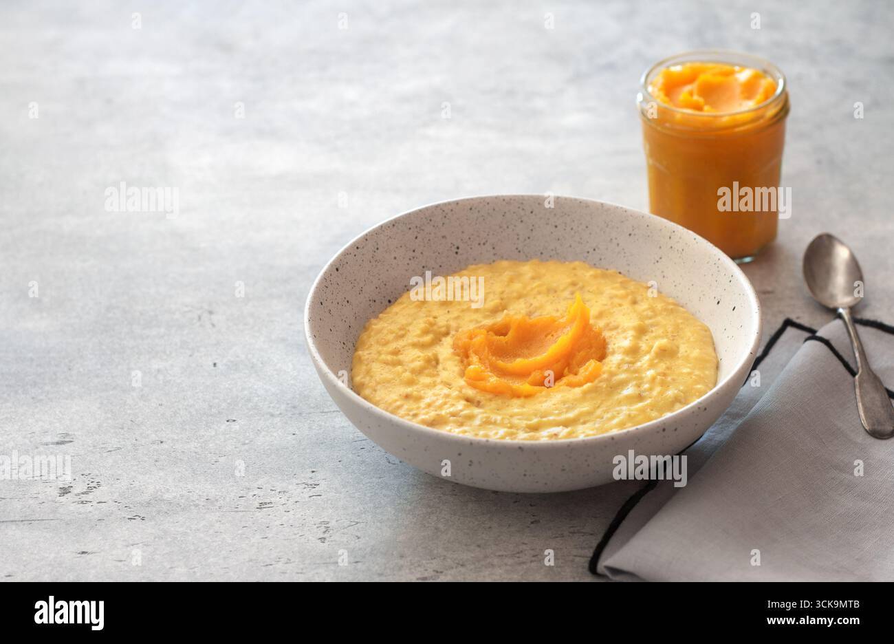 Bowl of oatmeal with pumpkin on a gray textured background. Delicious healthy homemade breakfast Stock Photo