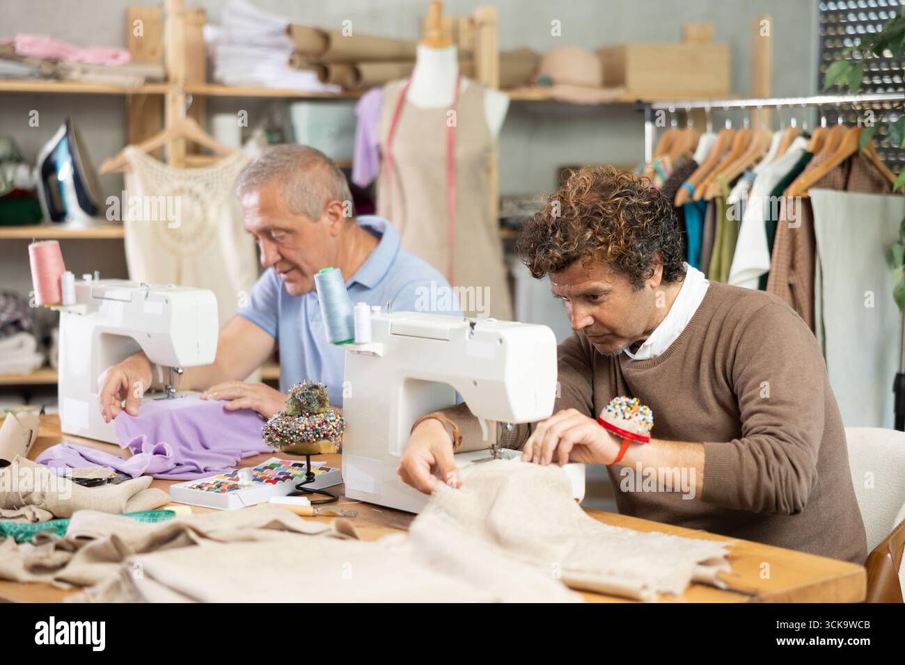 Two tailors sitting in a sewing workshop and working Stock Photo