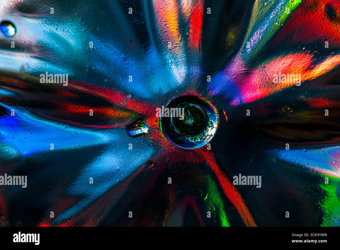 A vibrant close-up of crystal glass under direct light, showing radiant refractions and abstract patterns in red, blue, green, yellow, and orange hues Stock Photo